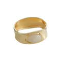 Wide gold-colored cuff bracelet with an elegant oval marble-patterned stone accent. - Wide Marble Pattern Gemstone Metal Bracelet (B4046)