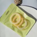 Detailed view of colorful phone cord hair ties in green bag on plate, cute and durable. - Macaron 4-Piece Set (Yellow)