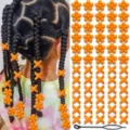 Detailed view of orange acrylic hair beads and X-shaped clips with a pulling tool for braids. - Orange