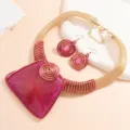 Scatto dettagliato del set collana e orecchini con gemme in acrilico e filo metallico esagerato. - Rosso rosa