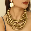 Detailansicht eines boho mehrschichtigen Holzperlen Halsketten und goldenen Ohrringe Sets. - Gold