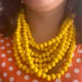 Gros plan detaille sur un collier multicouche en perles de bois jaune style ethnique. - Jaune