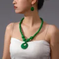 Detailopname van de groene houten kralenketting en bijpassende oorbellen gedragen. - Groen