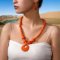 Detailopname van de levendige oranje houten kralenketting en passende oorbellen in een scène. - Oranje