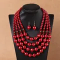 Gedetailleerde close-up van de rode kunstparel ketting met bijpassende oorbellen setje. - Rood