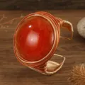 Gedetailleerd overzicht van handgemaakte aluminium draad brede manchet armband met grote harssteen. - Oranjerood