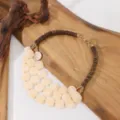 Gedetailleerd overzicht van een meerlaagse acrylschijf en houten kralen statement ketting. - Broken Wit