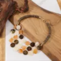 Gedetailleerd overzicht van meervoudige houten kralen en acryl ketting op houten rekwisiet. - Gemengde Koffie