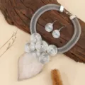 Close-up detail of silver-tone wire mesh statement necklace and matching spiral earrings. - White