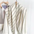 Detailaufnahme eines eleganten beigen Dreieckschals mit klassischen schwarzen Streifen. - Beige