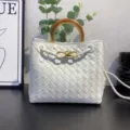 White woven leather handbag with metal wood handle and knot detail for women daily commute. - White