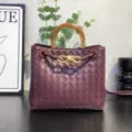 Luxury dark red woven leather handbag with wooden metal handle and chic knot detail for women. - Burgundy