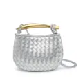 Detailopname van zilveren geweven leren minihandtas met gouden sculpturale handgreep. - Zilver