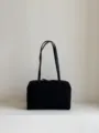 Detailed view of the black leather bowling bag featuring structured design and dual handles. - Canvas Black