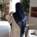 Elegant chiffon hijab and pleated dress detail with feather cuffs in indoor setting. - Navy Blue