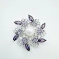Gedetailleerde close-up van een bloemvormige parelhanger met paarse en heldere zirkonia's. - Sneeuwvlok Brosche - Zilver - Kunstparel