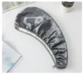 Close-up detail of the dark grey double-layer silk and fleece hair drying cap on flat surface. - Gray