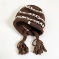 Brown knit earflap beanie hat with white pattern stripes and braided tassels for winter warmth. - One Size / Brown