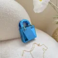 Primo piano dettagliato di una mini borsa a mano blu lucida con manici in metallo e catena. - Blu