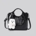 Elegante borsa nera in pelle intrecciata con ciondolo a forma di cagnolino peluche chic. - Nero