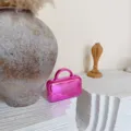 Primo piano di una mini borsa a mano metallica rosa lucida su un elegante piedistallo. - 15.5*5.5*13.5cm / Rosa