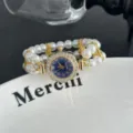 Vista detallada de un reloj de cuarzo con esfera floral de pedrería y pulsera de perlas. - Azul