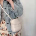 Minimalist grey crossbody saddle bag detail shot, versatile fashion shell handbag for women. - Off White