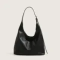Black leather hobo shoulder bag featuring minimalist design, spacious interior, and adjustable strap. - Black