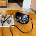 Detail view of the black owl leather crossbody bag featuring pearl tassels and metal lock. - Black