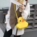 Close-up detail of the cute yellow duck hard shell crossbody bag, fashion cartoon style accessory. - Yellow