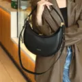 Black crescent underarm shoulder bag with metal hardware, premium commuter style variant. - Black