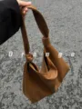 Detailed shot of brown leather slouchy shoulder bag with stylish knot handle design. - Brown