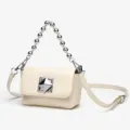 Close-up of elegant cream white crossbody bag with metal bead handle and chic pyramid clasp. - Off White