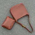 Detailed view of the brown slouchy hobo shoulder bag with matching pouch on textured ground. - Brown