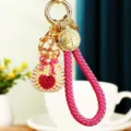 Cute rhinestone heart money bag keychain featuring pink braided strap and elegant gold metal ring. - Woven Rope Pearl Heart Lucky Bag / Rose Red