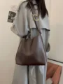 Close-up detail of a brown slouchy hobo shoulder bag with a gold metal buckle strap. - Coffee