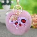 Close-up of cute plush sheep keychain with sparkling rhinestones and pink pom-pom pendant. - Purple Rhinestone Sheep + Violet Plush Ball