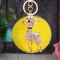 Detailed shot of sparkling rhinestone ram keychain with fluffy yellow pom pom and gold hardware. - White Goat with Yellow Plush Ball