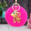 Detailed close-up of a sparkling rhinestone ram keychain with hot pink fluffy pom-pom charm. - Lucky Pink Sheep + Rose Red Plush Ball