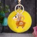 Close-up detail view of the sparkling rhinestone sheep keychain with fluffy yellow pom-pom. - Lucky Champagne Sheep + Yellow Plush Ball