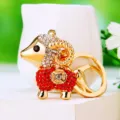 Detailed close-up of a glittering gold-plated sheep keychain with red and white crystal rhinestones. - Lucky Red Sheep
