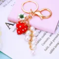 Portachiavi in metallo dorato con ciondolo fragola rossa in strass, fiore bianco e perle. - A803 Catena di Perle di Fragola