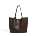 Detailed view of the dark brown leather tote bag showing fine texture and vertical seam design. - Coffee