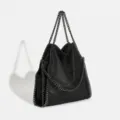 Detailed view of black chain-trimmed tote bag, soft fabric and metal chain details. - Black