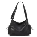Black slouchy shoulder bag detail showing soft leather texture, side pockets, and pleated strap. - Black