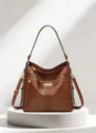 Close-up of brown soft leather bag showing perforated stripe detail and dual zipper pockets. - Dark Brown