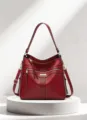 Detailed view of the elegant red leather shoulder bag featuring multi zippers and tassels. - Red