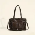 Close-up detail of retro dark brown leather shoulder bag with metal buckles and front pocket. - Coffee