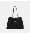 Black corduroy tote bag detail showing soft textured fabric, durable chain straps, and attached pouch. - Black