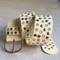 Detailed view of women's punk style PU leather wide belt with metal grommets and large buckle. - Beige Yellow